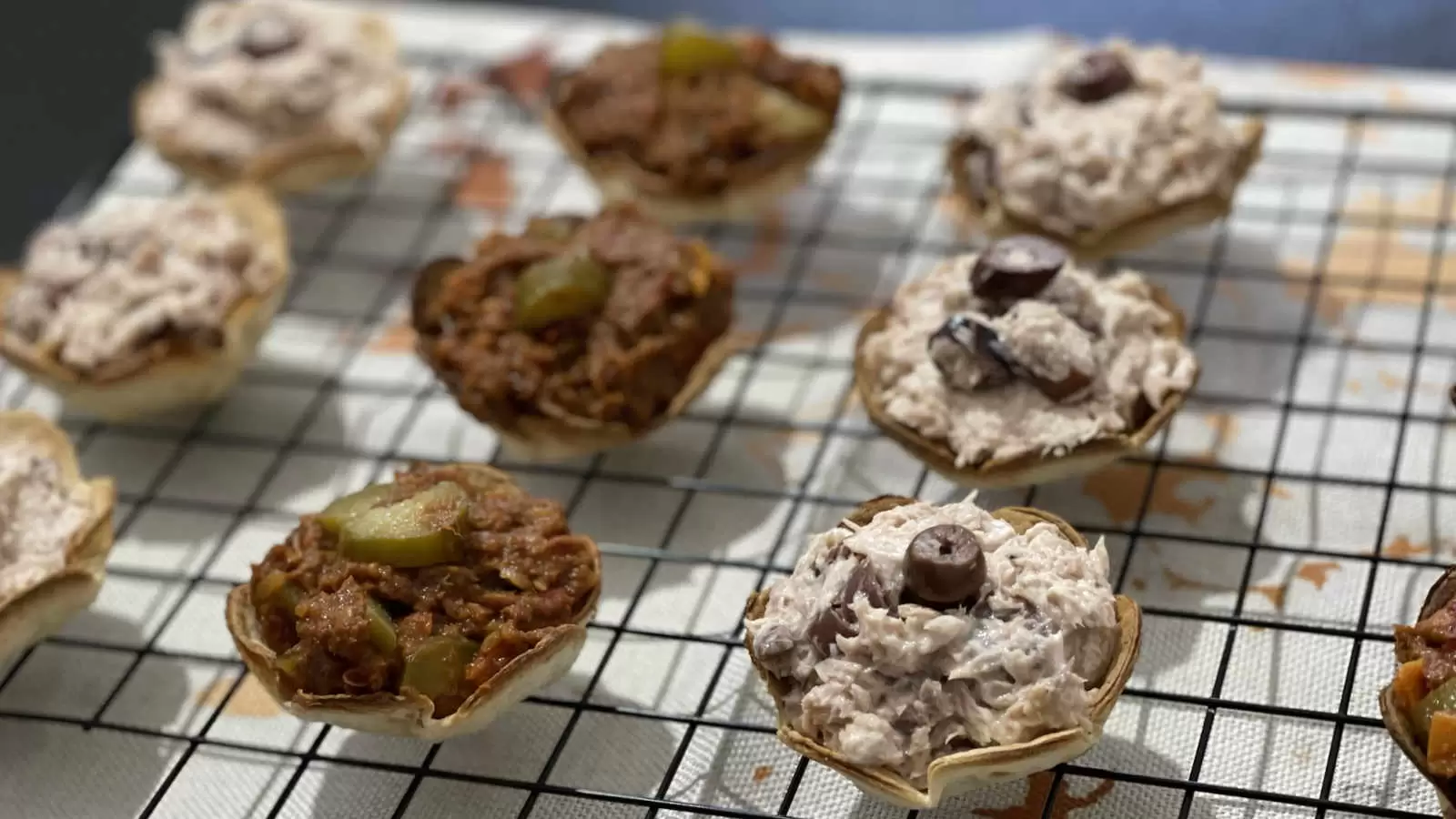 Tortilla flowers filled with tuna on a cooling rack and under a napkin