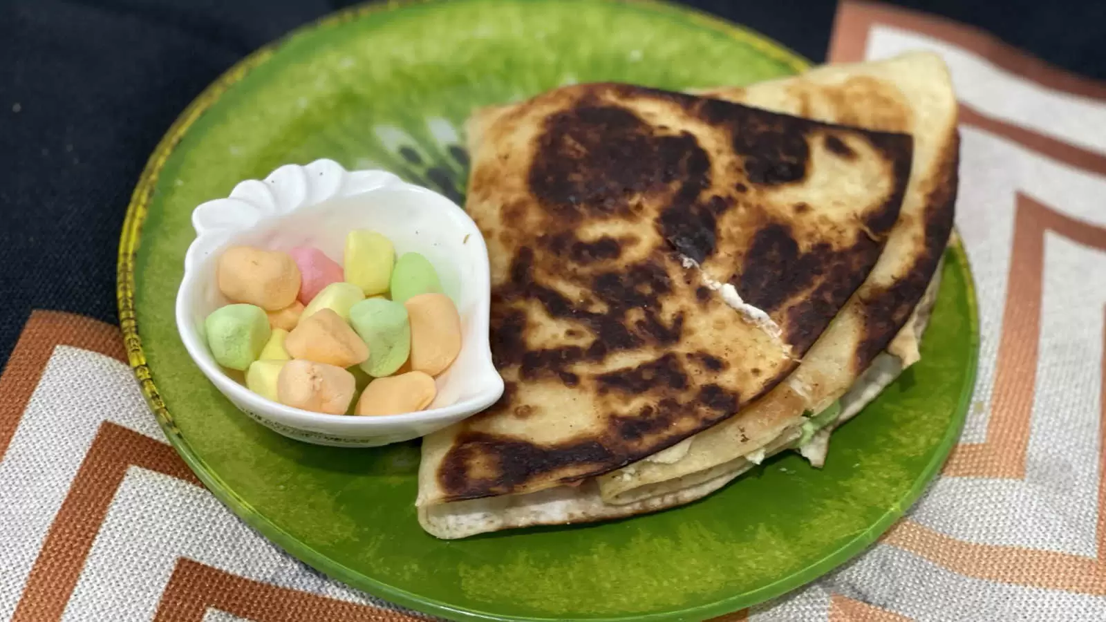 Tortilla Smores on a plate a bowl with marshmallows on a green plate on a striped napkin