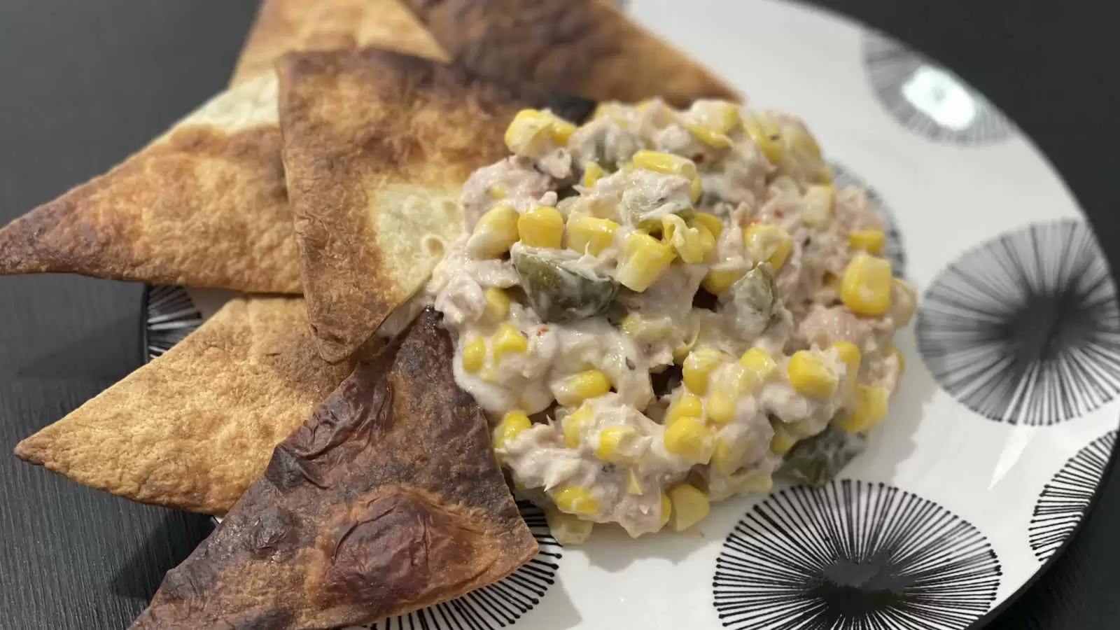 Tuna corn and mayonnaise salad dish on a plate and tortilla triangles